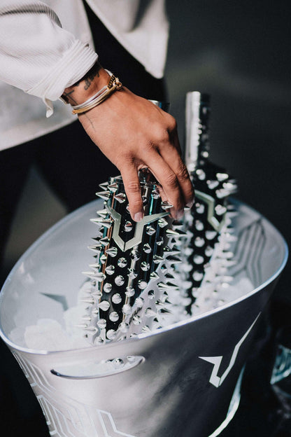 Person holding stylish, spiked bottles from a metallic ice bucket, highlighting unique and edgy design.